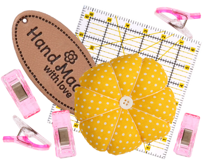 The 8 Free Digital Pattern Bundle is displayed alongside sewing accessories—including a yellow polka dot pincushion, sewing label, pink clips, and a clear quilting ruler—arranged on a white background.