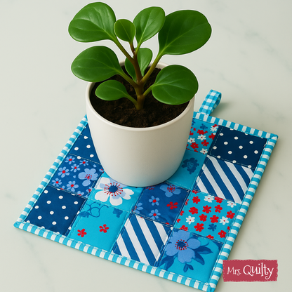 A decorative potholder made with the Pot Holder Downloadable PDF Quilt Pattern features a small green plant in a white pot, displayed on a blue and white patchwork quilted mat labeled "Mrs. Quilty.