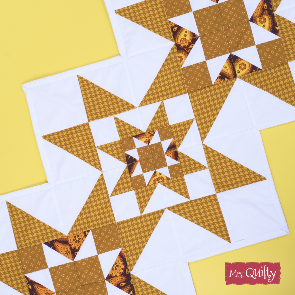 Table Runner Downloadable PDF Quilt Pattern features brown and white star patchwork blocks on a yellow background. Ideal for home decor, this easy-to-download pattern includes the “Mrs. Quilty” label in the bottom right corner.
